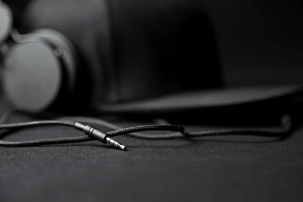 Чорні навушники з капелюхом на чорному тлі — стокове фото