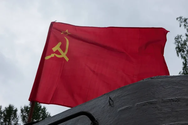 Yeşil tankın üzerinde çekiç ve orakla dalgalanan kırmızı bir Sovyet bayrağı. Geçmişi. Doku.