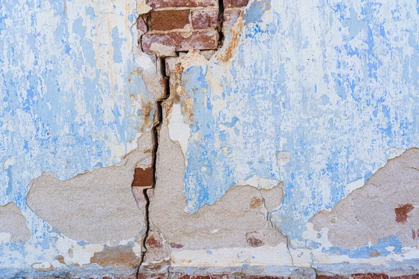 Eski bir tuğla evin duvarının parçası. Büyük bir çatlak var. Sıva ve mavi boya kalıntıları görülebilir. Geçmişi. Doku. 
