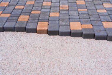 Gri ve sarı asfalt levhalar bir kum karışımının hazırlanmış yüzeyine konur. Döşeme kaldırımının kenarı görünür. Geçmişi. Kum ve çimento bloklarının dokusu. 