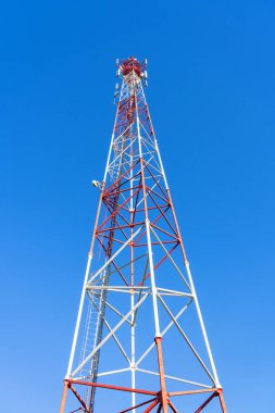 Baz istasyonunun alt görüntüsü. Açık mavi gökyüzüne karşı kırmızı ve beyaz metal yapı. Geçmişi. Dikey çerçeve. 