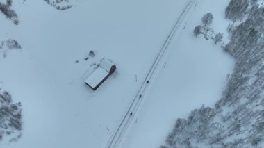 Donmuş bir nehri geçen dar bir yol köprüsünün yer aldığı karla kaplı bir arazinin havadan görünüşü. Drone, 4k