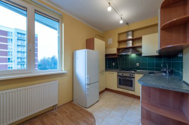 Klasik Eski Usul Ev Mutfağı İçi. Fırın, lavabo, pencereler, buzdolabı. İskandinav Tasarımı. Led Lights, Döşeme Döşemesi. Sarı Duvarlar. Pencerenin Altındaki Isıtıcı. Dolaplar ve Dolaplar. Geniş Açı