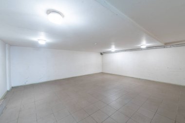 Döşeme, beyaz duvarlar ve tavan lambalarının yer aldığı aydınlatılmış boş bir oda, yaratıcı kullanım veya depolama amacıyla ideal