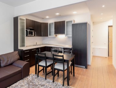 Parlak ve modern mutfak ve ahşap döşemeli oturma odası, modern mobilyalar ve rahat bir atmosferle tasarlandı..