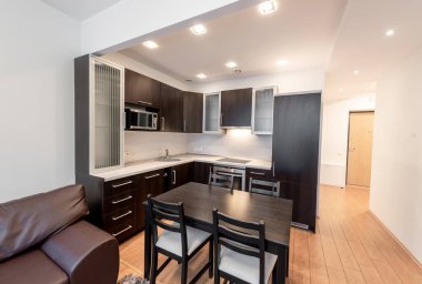 Parlak ve modern mutfak ve ahşap döşemeli oturma odası, modern mobilyalar ve rahat bir atmosferle tasarlandı..