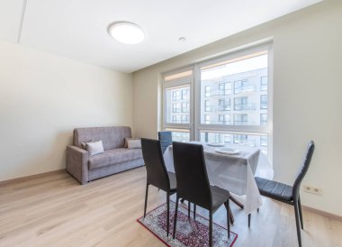 Geniş pencereli geniş bir yemek alanı. Geniş doğal ışık, masa, sandalye ve çağdaş bir alanda bir kanepe..