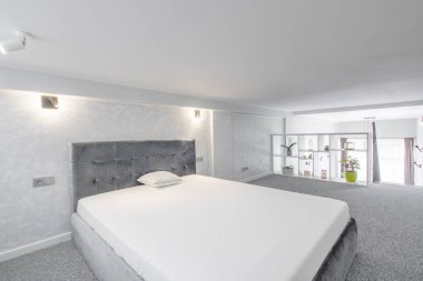 Rahat bir yatağı, modern dekorasyon unsurları ve doğal ışıklandırması olan parlak, temiz bir çatı katı. Minimalist iç tasarımı sergilemek ve rahatlamayı teşvik etmek için mükemmel bir ortam.