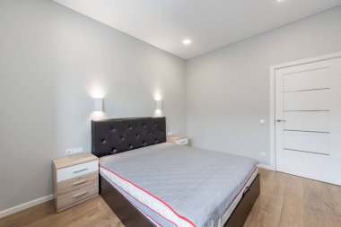 Konforlu bir yatak odası, şık bir ışıklandırma ve şık mobilyalar, parlak ve davetkar bir yer yaratıyor.