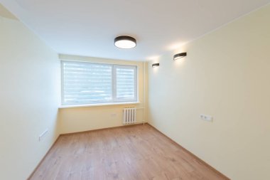 Parlak, minimalist, ahşap döşemeli, geniş pencereli ve modern aydınlatma aletli boş bir oda..