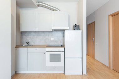 Beyaz dolap, döşeme döşemesi, ahşap döşeme, temiz ve işlevsel bir iç tasarım sergilenen parlak modern mutfak.