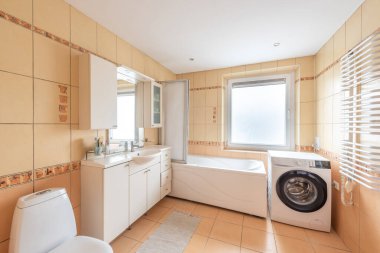 Geniş ve temiz banyo küveti, çamaşır makinesi, geniş pencere ve temiz fayans dekorasyonu var..