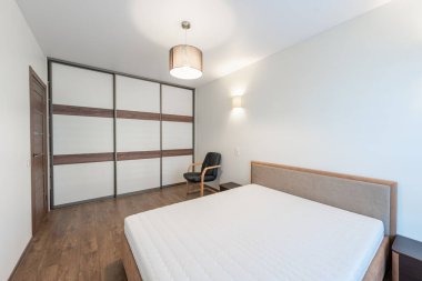 Temiz bir tasarımı, rahat bir yatağı ve pratik mobilyaları olan parlak ve minimalist bir yatak odası.