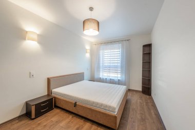 Zarif tasarlanmış yatak odası, minimalist mobilyalar, doğal ahşap döşemeler ve bol miktarda yumuşak ışıklandırma.