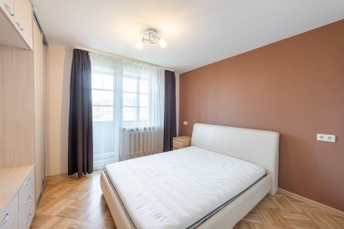 Zarif tasarlanmış yatak odası, minimalist mobilyalar, doğal ahşap döşemeler ve bol miktarda yumuşak ışıklandırma.