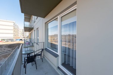 Şık mobilyaları olan iyi tasarlanmış bir balkon. Şehir manzaralı çağdaş bir konut binasının parçası.
