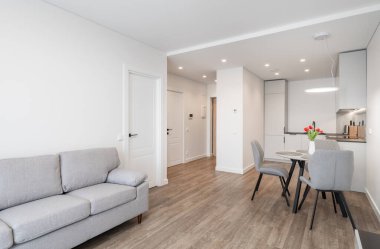 Parlak ve modern oturma odası, tarafsız mobilyalar ve ahşap döşemeler, rahatlamak için rahat ve şık bir iç mekan yaratıyor.