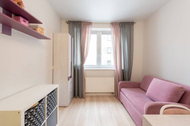 Pembe bir kanepesi, ahşap mobilyası, perdesi ve doğal ışığın odayı doldurmasına izin veren bir penceresi olan parlak minimalist bir iç mekan.