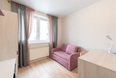 Pembe bir kanepesi, ahşap mobilyası, perdesi ve doğal ışığın odayı doldurmasına izin veren bir penceresi olan parlak minimalist bir iç mekan.