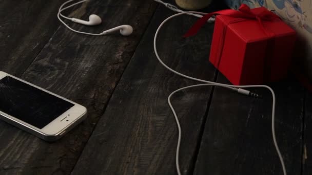 Em uma mesa escura é o telefone quebrado, skater, fones de ouvido, caixa vermelha — Vídeo de Stock