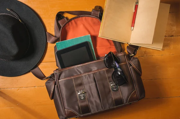 Travel accessories on wood: bag, vintage diary, sunglasses and hat