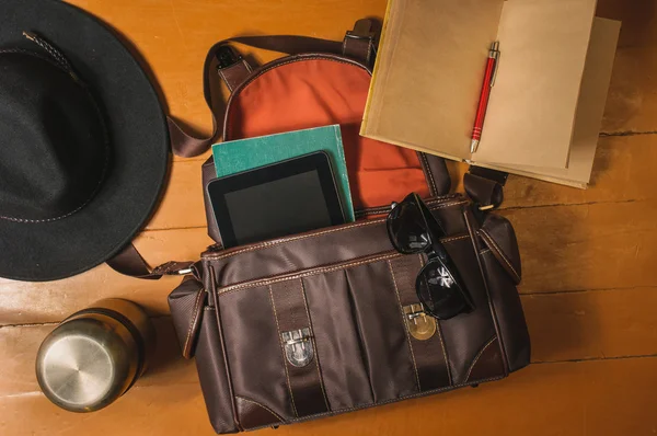 Travel accessories on wood: bag, vintage diary, sunglasses and hat