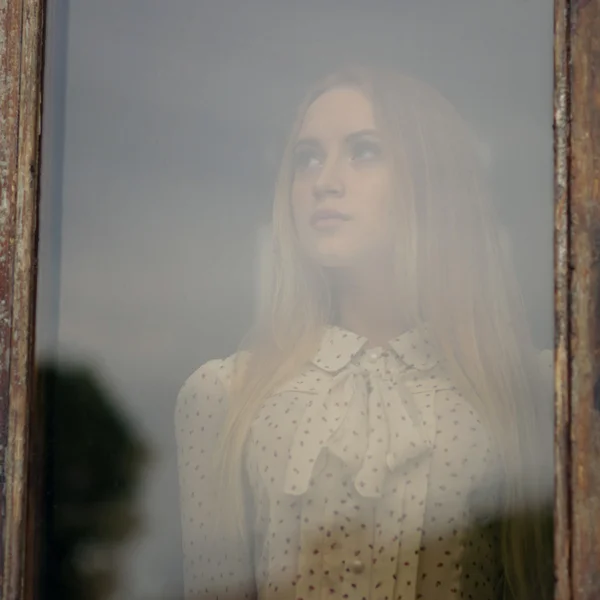 Porträtt av en vacker flicka tittar genom fönstret Royaltyfria Stockbilder