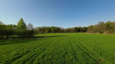 Nehir ve çayır üzerinde alçak ve hızlı bir İHA uçuşu.