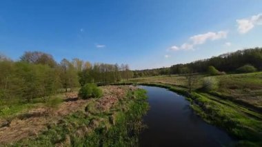 Nehir ve çayır üzerinde alçak ve hızlı bir İHA uçuşu.