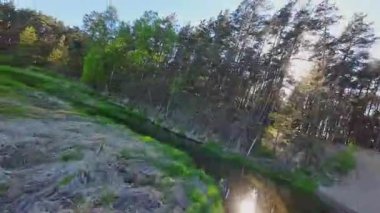 Nehir ve çayır üzerinde alçak ve hızlı bir İHA uçuşu.