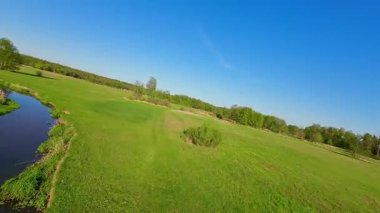 Nehir ve çayır üzerinde alçak ve hızlı bir İHA uçuşu.