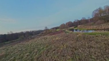 Nehir ve çayır üzerinde alçak ve hızlı bir İHA uçuşu.