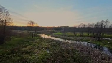 Nehir ve çayır üzerinde alçak ve hızlı bir İHA uçuşu.