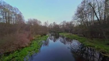 Nehir ve çayır üzerinde alçak ve hızlı bir İHA uçuşu.