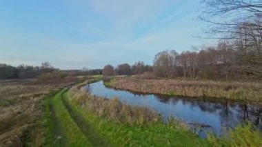 Nehir ve çayır üzerinde alçak ve hızlı bir İHA uçuşu.