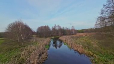 Nehir ve çayır üzerinde alçak ve hızlı bir İHA uçuşu.