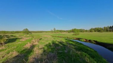 Nehir ve çayır üzerinde alçak ve hızlı bir İHA uçuşu.