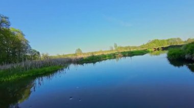 Nehir ve çayır üzerinde alçak ve hızlı bir İHA uçuşu.