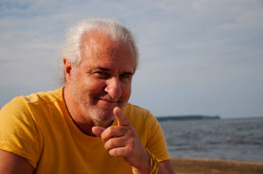 Özgürlük ve açık ufuk. Yazın gün batımında deniz sahilinde romantik bir adam. Emekliliğin tadını çıkarıyorum. Kıdemli yaşam tarzı. Gün batımında okyanus kıyısında olgun bir adam. İşaret parmağı.