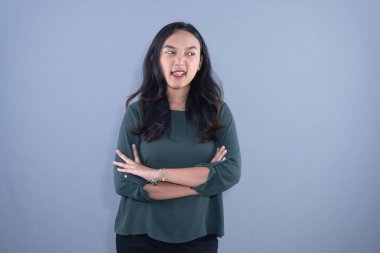 Yeşil bluzlu bir kadın kollarını kavuşturmuş, şakacı bir şekilde dilini uzatıyor.