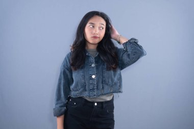 Kot ceketli genç bir kadın, kafa kafaya, düşünceli ve şaşkın bir ifadeyle başka yere bakar.