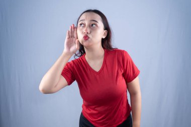 Kırmızı gömlekli bir kadın dikkatlice dinliyor, eli kulağına yapışık.