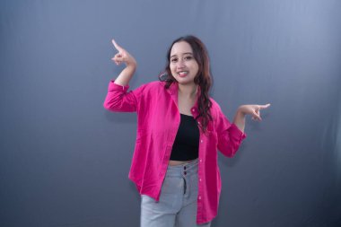 Pembe tişörtlü, gülümseyen bir kadın iki farklı yönü gösterir.