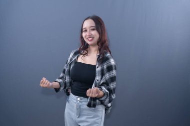 Siyah beyaz ekose gömlekli, gülümseyen genç bir kadın yumruğunu kutluyor.