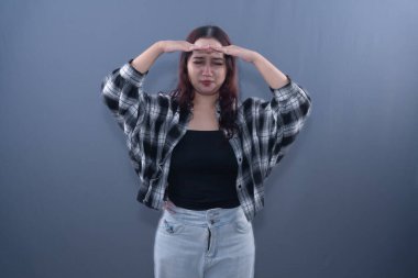 Siyah beyaz ekose gömlekli başı ağrıyan bir kadın başını dertten kurtaramaz.