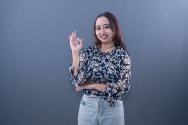 Lacivert gömlekli bir kadın el hareketi yaparken gülümsüyor.