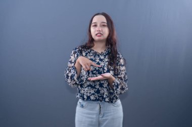 Hafif bir acı çeken bir kadın sağ işaret parmağıyla sol avuç içini işaret ediyor.