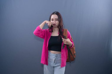 Pembe gömlekli bir kadın iğrenç bir ifadeyle burnunu çimdikliyor.