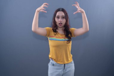 Sarı gömlekli bir kadın 'canavar pençesi' pozu veriyor.