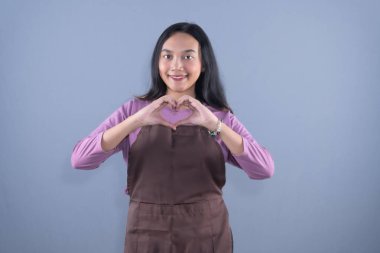 Şef şapkası ve kahverengi önlük takan bir kadın kollarıyla X işareti yapıyor.